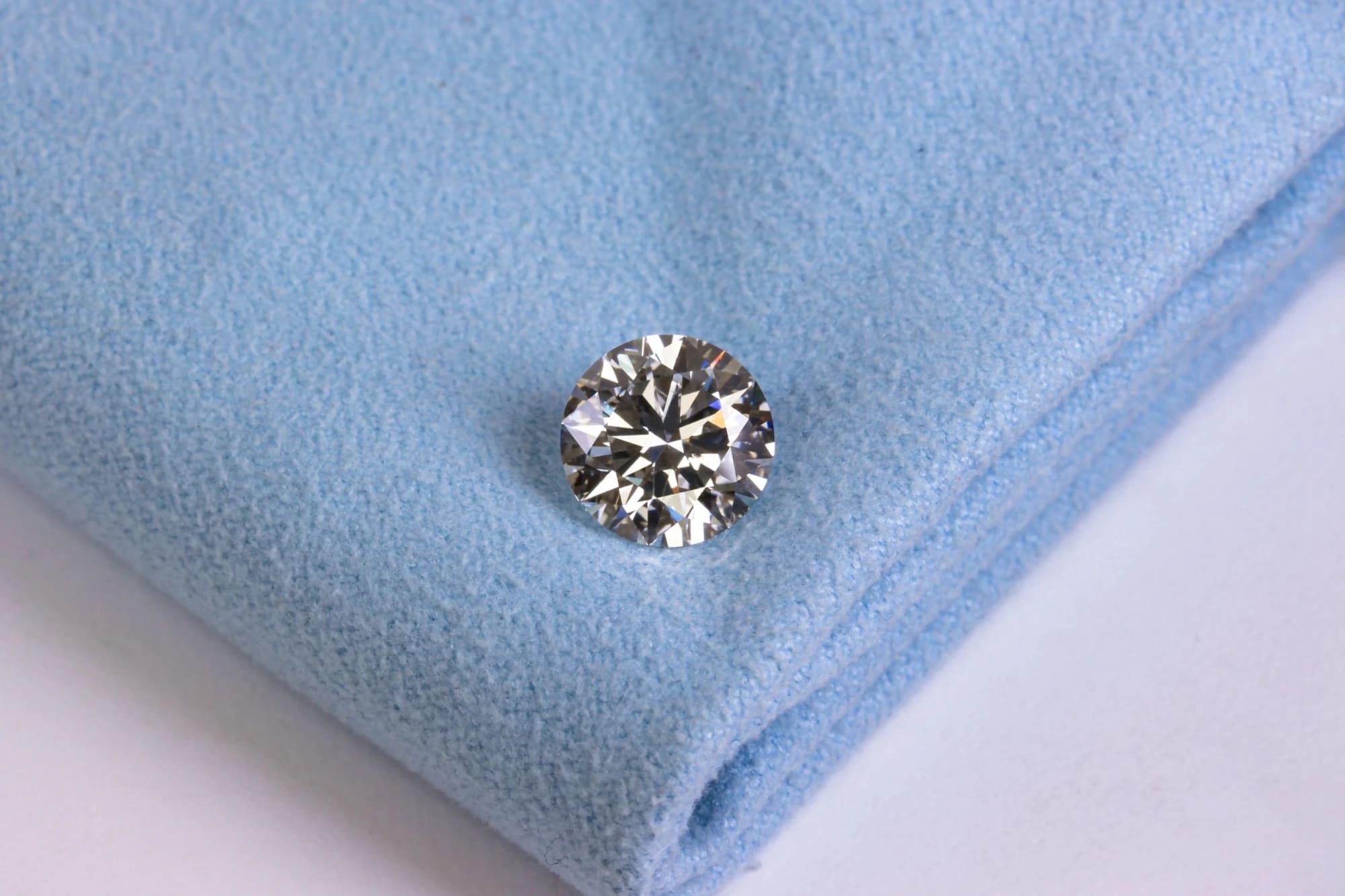 Sparkling round diamond resting on light blue cloth
