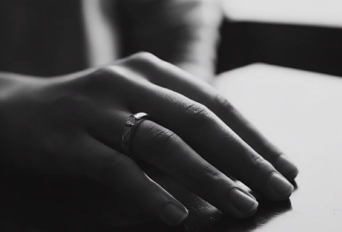 facetsn close-up of hand wearing lab-grown diamond solitaire ring in black and white