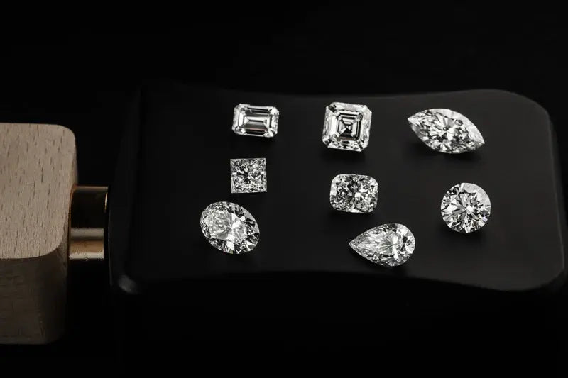 facetsn loose lab-grown diamonds in multiple shapes on black jeweler's tray