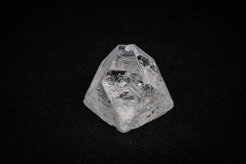 facetsn rough mined diamond crystal with visible inclusions on black fabric background